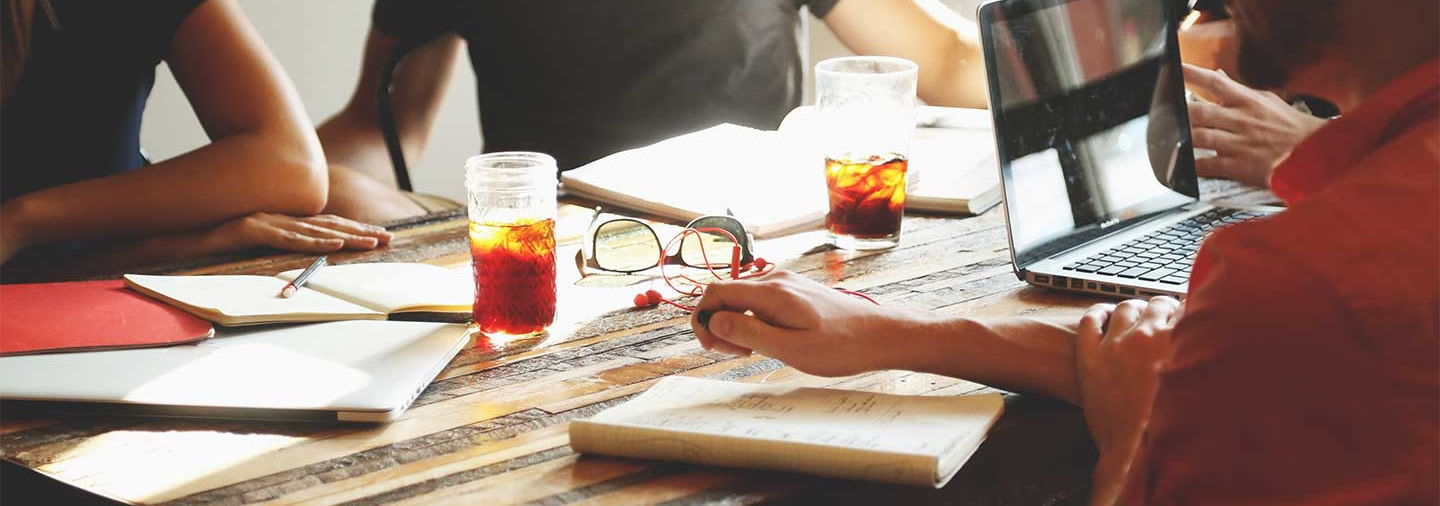 An aerial view of a team working on various projects, with their hands and tools visible at a wooden table.